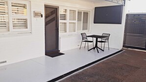A covered patio with a table and chairs, a door, and a window with blinds. - Beachside Homely Flat in Rockingham (Rockingham)