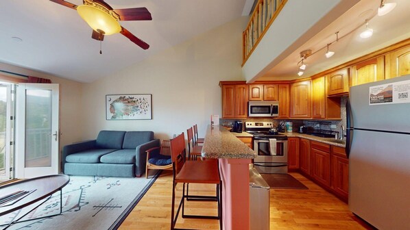 A compact kitchen with wooden cabinets, a microwave, stove, and a refrigerator.