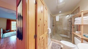 A modern bathroom with a glass-enclosed shower, wooden cabinets, and a visible toilet.