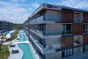 Experience the GAV RESORTS' contemporary design, featuring a multi-story building with large windows and a curved swimming pool.
