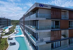 Experience the GAV RESORTS' contemporary design, featuring a multi-story building with large windows and a curved swimming pool.
