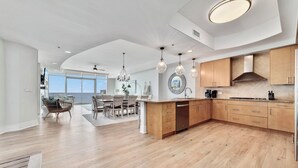 A spacious kitchen with wooden cabinets, a central island, and pendant lighting. - Turquoise Place D1008 | Gorgeous Updates! Oversized, hot tub/grill on deck, huge slide for kids! (Orange Beach)