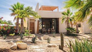 Ein modernes Haus mit Terrasse, Palmen und Garten.