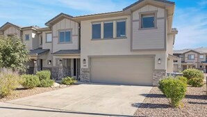 A modern two-story residential building with a garage, a driveway, and landscaped garden areas.