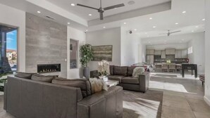 A spacious living area with a fireplace, a large sofa, and a view into the kitchen.