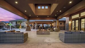 An outdoor patio area with a fire pit, wicker furniture, and a stone fireplace.