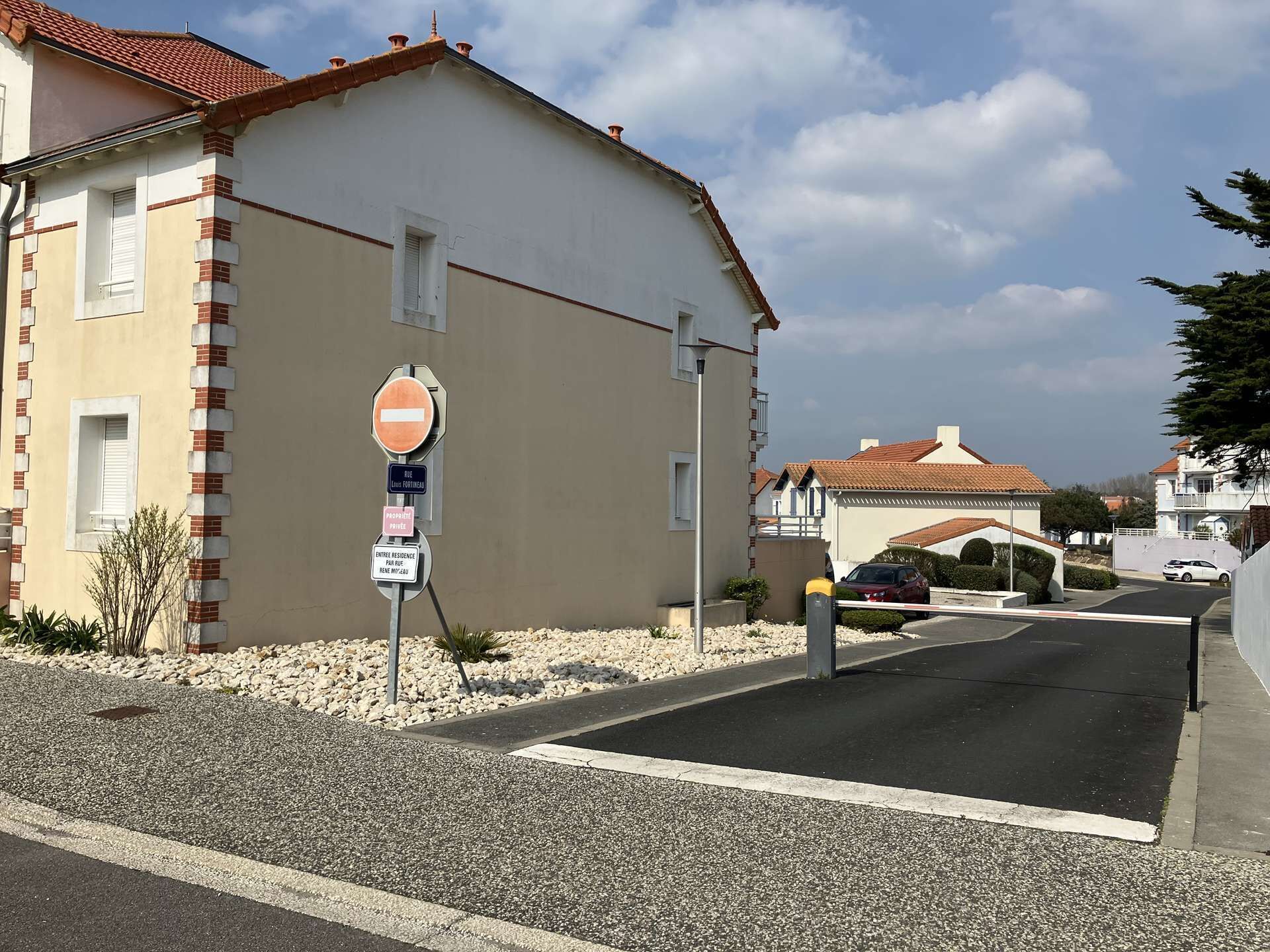 Un carrer residencial amb una casa que té un teulat de rajoles vermelles, un senyal de prohibit l'entrada i una indicació que es tracta d'una propietat privada.