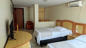 Una habitación de hotel con dos camas, un escritorio, un televisor y un aire acondicionado.