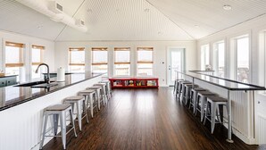 A spacious kitchen with a central island, bar stools, and a red bench. - 1 Block from the Beach, Entertainment Deck with games and Tv, large enough for 26 guests. (Bolivar Peninsula)