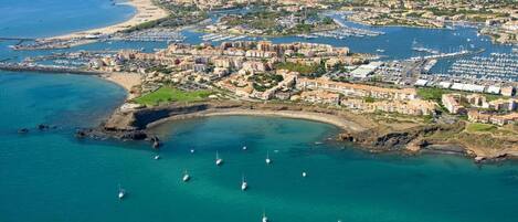 An aerial view of a coastal city with a marina, buildings, and boats.