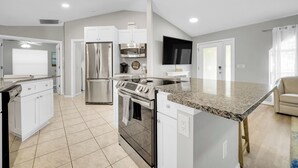 Una cocina moderna con armarios blancos, electrodomésticos de acero inoxidable y encimera de granito.