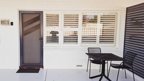 Zona de terrassa amb una porta, una taula i dues cadires.