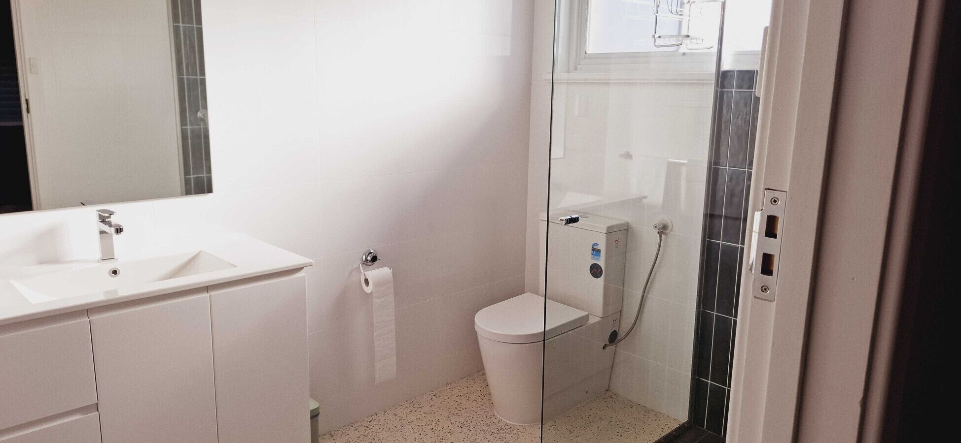 A bathroom with a white sink, toilet, and shower area.