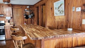 Una cucina con mobili in legno, un piano di lavoro in legno e un angolo bar con sgabelli.