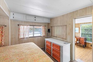 A bedroom with a bed, a dresser, a desk, and a window with curtains. - Canal Front Home in Gated Community. Salt Life #182 (Cudjoe Key)