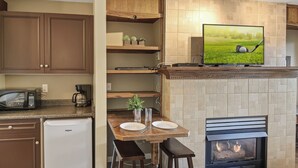 Una cocina con televisor integrado, chimenea y zona de comedor con taburetes.
