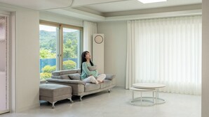 A modern living room with a sofa, a round table, and large windows with curtains. - Gapyeong Dream Pool Villa Pension (Gapyeong)
