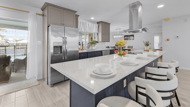 A modern kitchen with a large island, stainless steel appliances, and a view to the outside. - Direct Gulf Access, Heated Pool - Sunshine Getaway - Roelens (Cape Coral)
