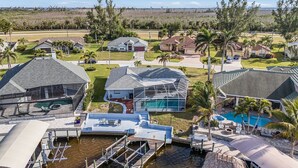 A residential area with houses, a swimming pool, and a dock. - Direct Gulf Access, Heated Pool - Sunshine Getaway - Roelens (Cape Coral)