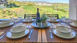 A table set for dining with a view of a golf course and mountains.