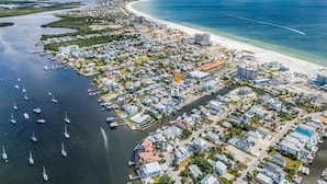 Vista aérea de uma área residencial costeira com um porto de iates, casas e uma praia.