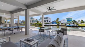 Uma área de estar moderna ao ar livre, com piscina, assentos e vista para edifícios próximos.
