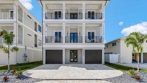Um edifício residencial com vários andares, entrada central, duas garagens e varandas em cada pavimento.