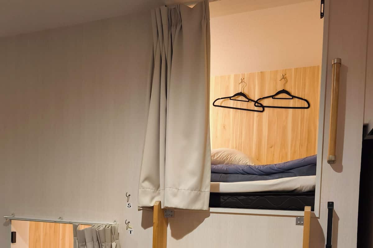 A bunk bed with a wooden headboard, a pull-out desk, and a wardrobe with a mirror.