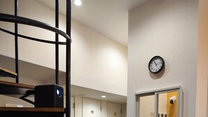 A modern interior with a spiral staircase, a clock on the wall, and a window with a view of the outside. - KOREGA Hostel Osaka Namba - Hostel (Osaka)