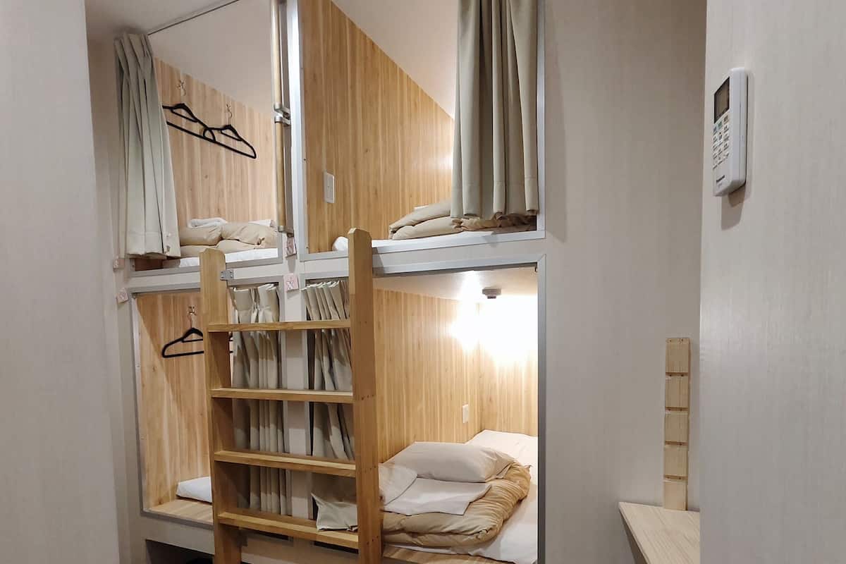 A bunk bed room with wooden walls, a desk, and a chair.