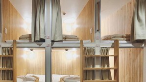 A bunk bed room with wooden walls and curtains. There are two bunk beds, each with a ladder and pillows. - KOREGA Hostel Osaka Namba - Hostel (Osaka)