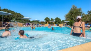 A swimming pool with people swimming and lounging under umbrellas.