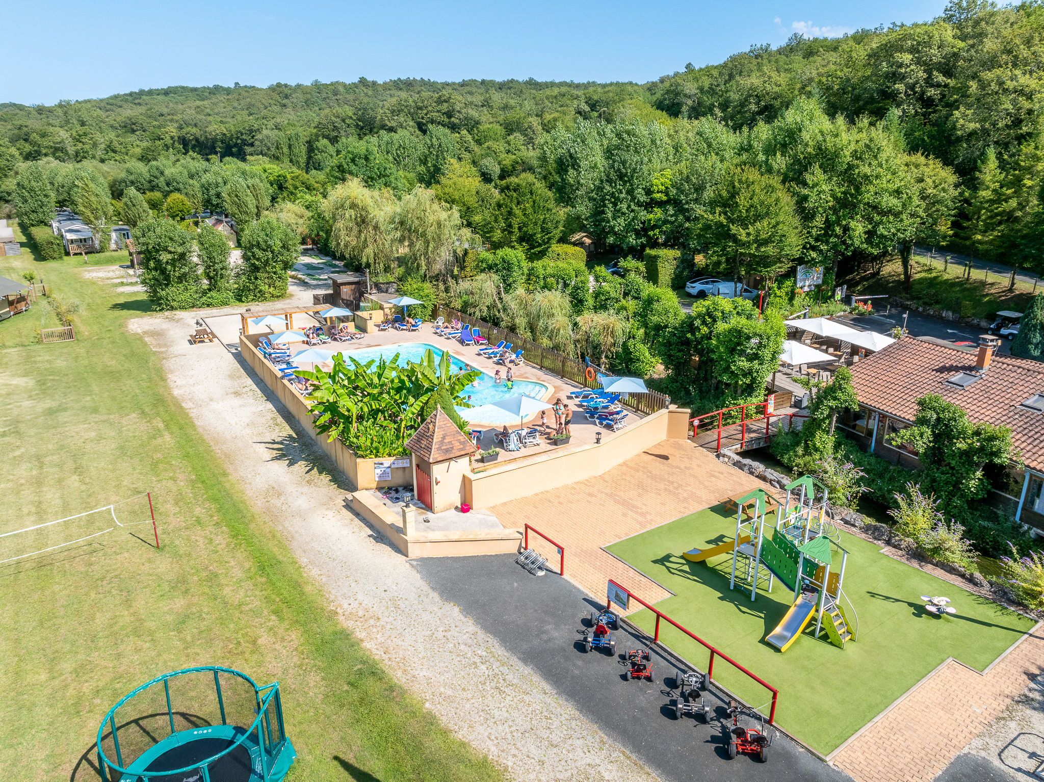 Un resort con piscina, mobiliario exterior y área de juegos.