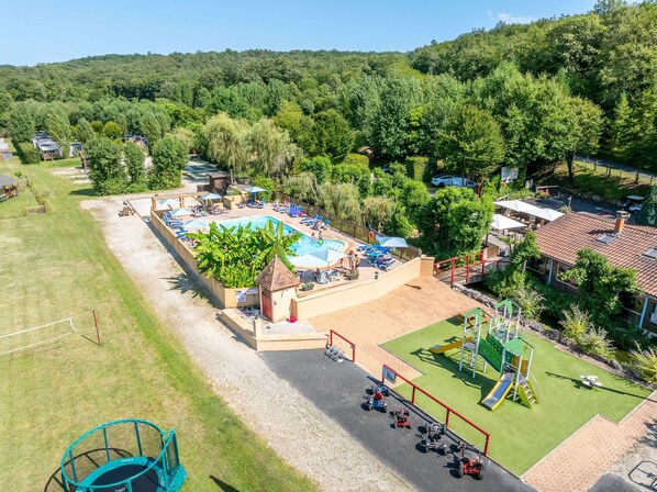 A resort with a swimming pool, outdoor seating, and a playground.