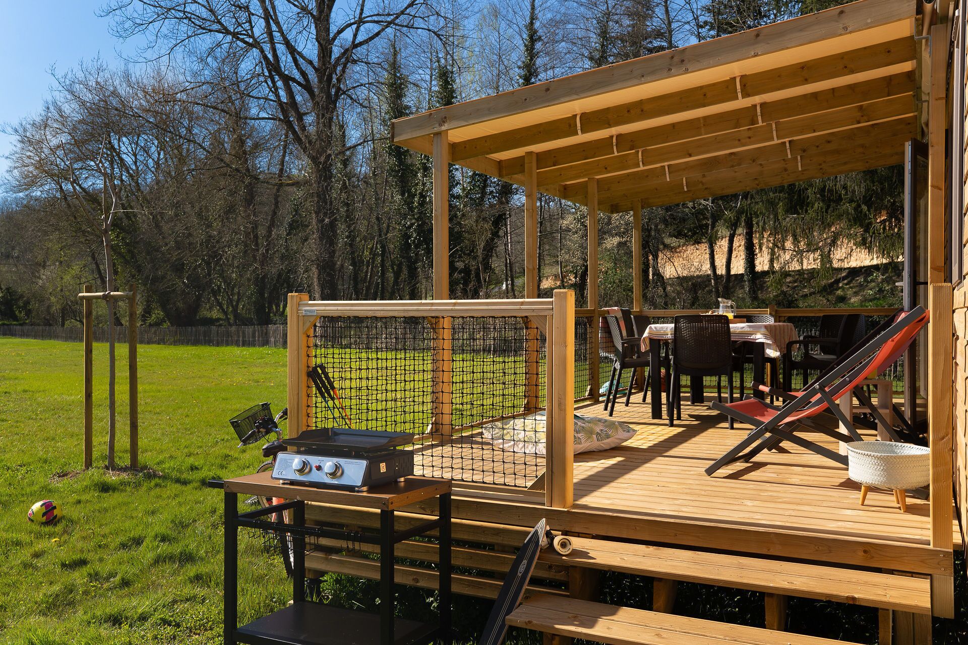 Eine Holzterrasse mit Grill, Stühlen und einem Tisch.