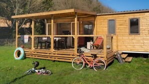A wooden cabin with a covered porch, a bicycle, and a tire swing.