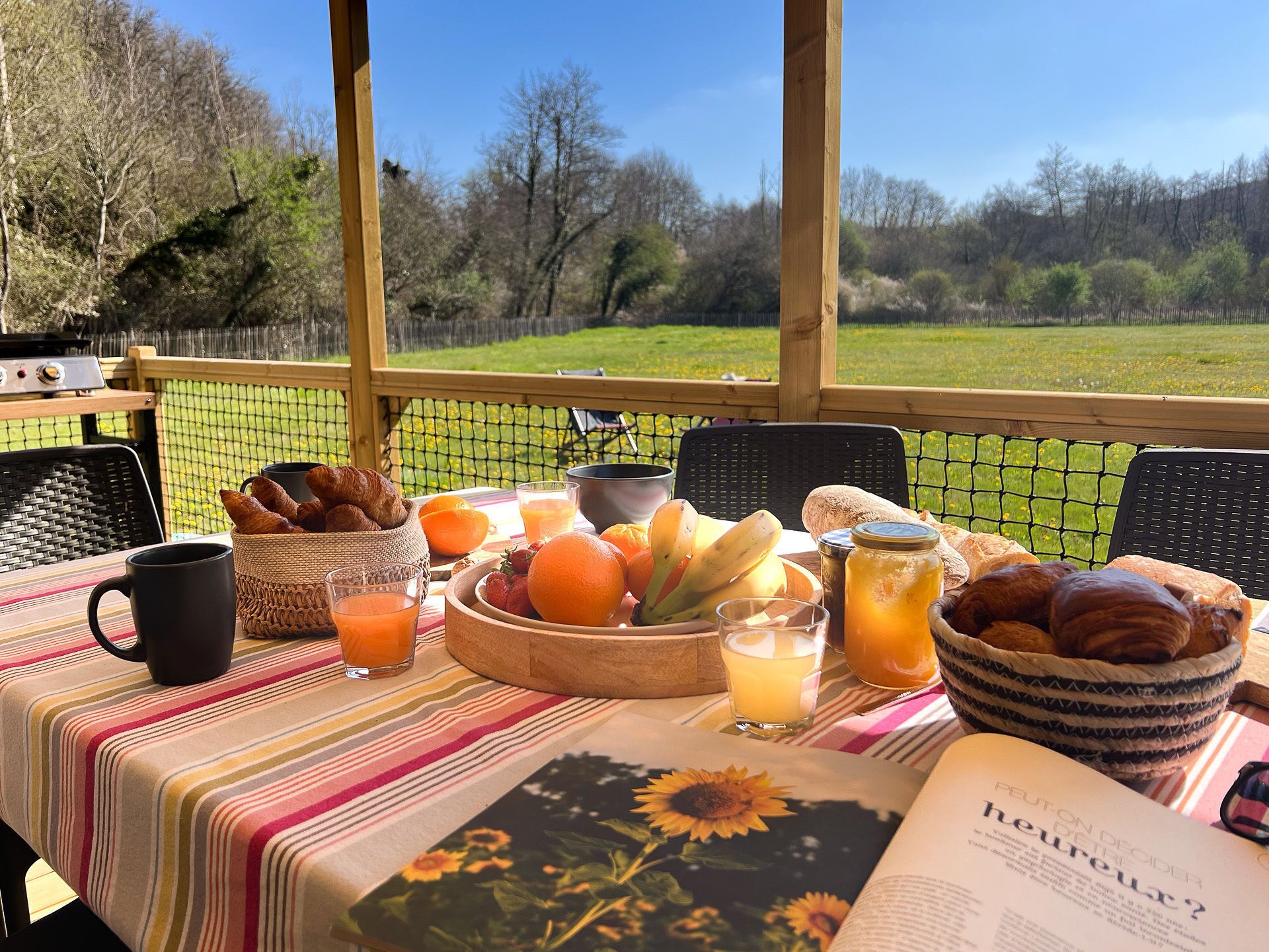 Una mesa de desayuno con cruasanes, naranjas, plátanos y un libro titulado 'Heureux'.