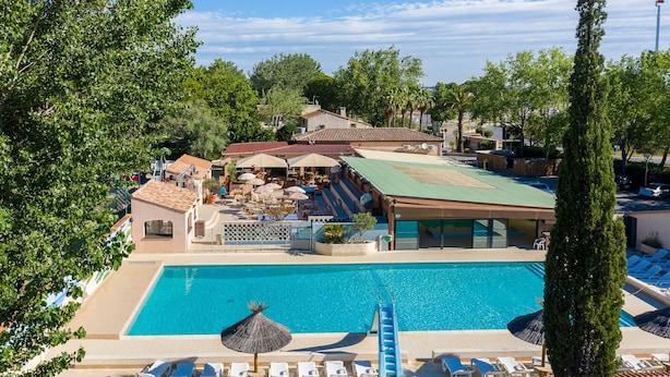 A resort with a swimming pool, outdoor seating, and a covered patio area.