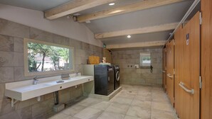 A modern bathroom with a large mirror, two sinks, a washing machine, and wooden cabinets.