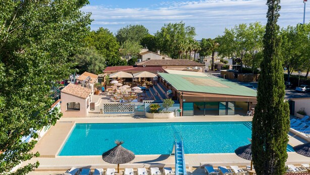 A resort with a swimming pool, outdoor seating, and a covered patio area.
