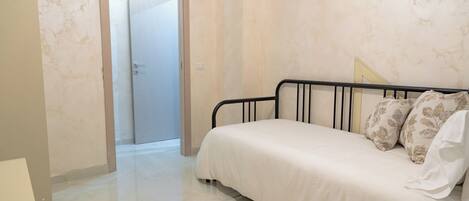 A bedroom with a bed, a door, and a light switch on the wall.
