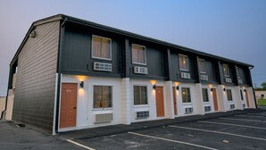 A multi-story motel with a row of rooms, each with a door and window.