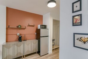 A compact kitchen with a microwave, refrigerator, and a wooden cabinet. There are framed artworks on the wall. - Room 101 - King, NonSmoking (Lincoln)