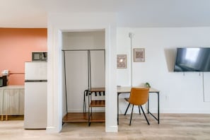 Un espace de vie moderne comprenant un coin cuisine, une table à manger avec une chaise et un téléviseur fixé au mur.