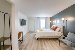 Une chambre à coucher moderne, comprenant un lit, un bureau, une chaise, un téléviseur et une lampe de chevet.