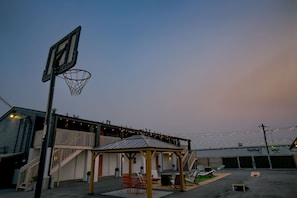 A basketball court with a hoop, a covered seating area, and string lights. - Room 101 - King, NonSmoking (Lincoln)