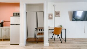 A modern living space with a kitchen area, a dining table with a chair, and a mounted television.