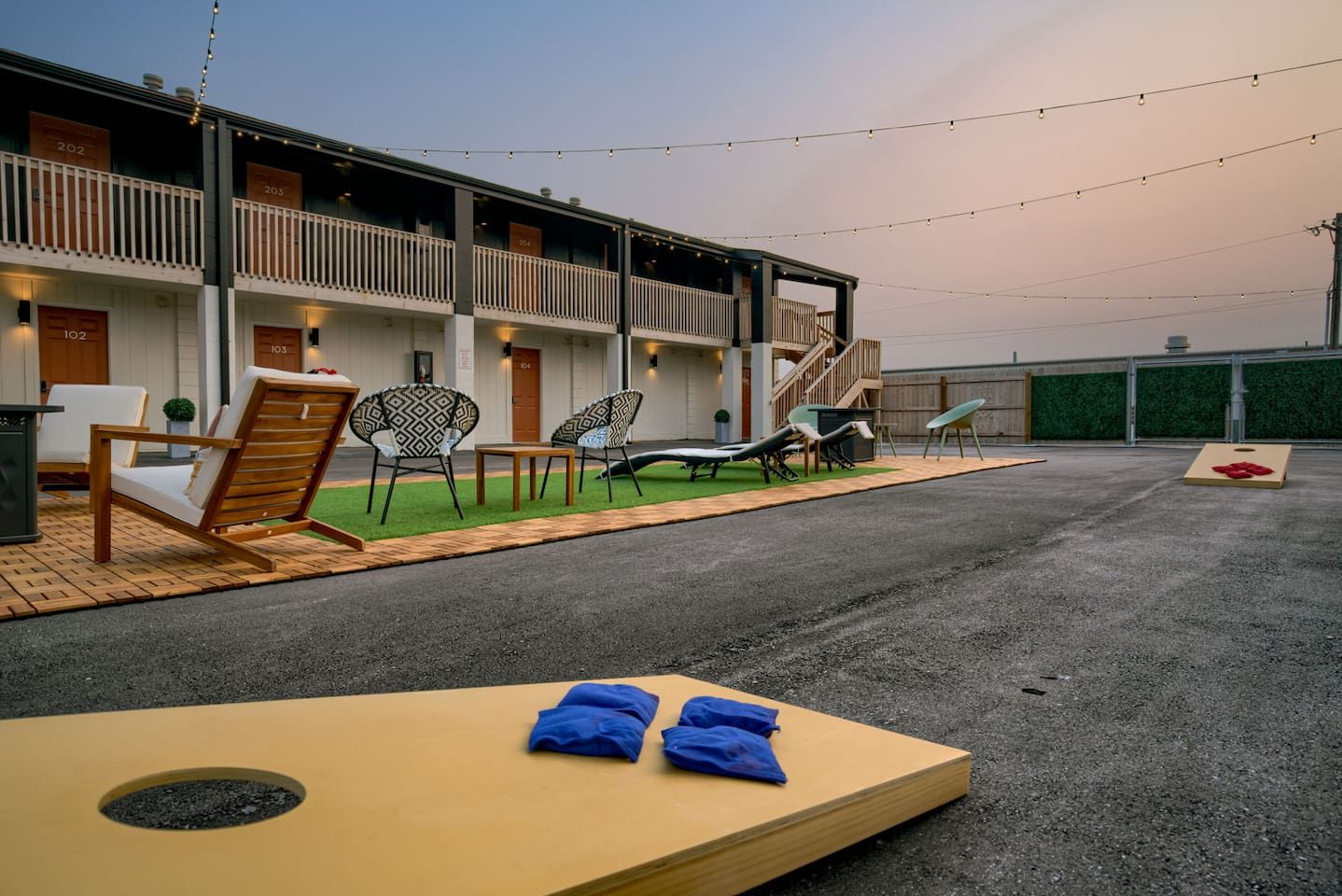 Un hotel con mesas y sillas al aire libre, incluyendo sillones de descanso y una mesa con toallas.