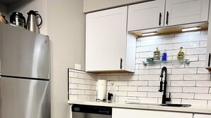 A modern kitchen with white cabinets, a stainless steel refrigerator, a dishwasher, and a tiled backsplash. - Airport,ASU,Cubs,WMGopen,fast fiber Wi-Fi, 2desks, balcony, king bed (Tempe)