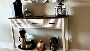 A kitchen area with a white console table, various kitchen appliances, and decorative plates on the wall. - Airport,ASU,Cubs,WMGopen,fast fiber Wi-Fi, 2desks, balcony, king bed (Tempe)